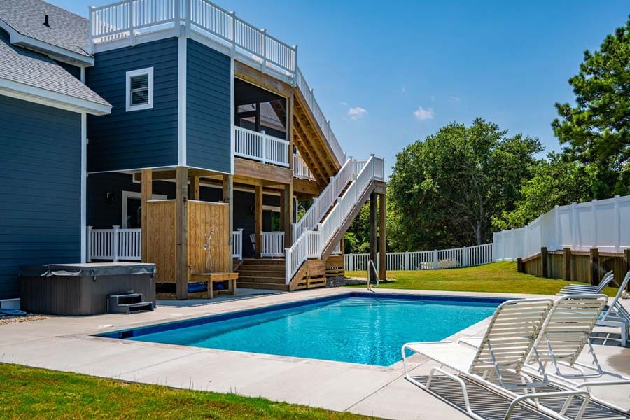 Back Exterior with White Fence and Large Pool of a Modern Colonial House Design and Construction by Premiere Contracting, Inc. Outer Banks